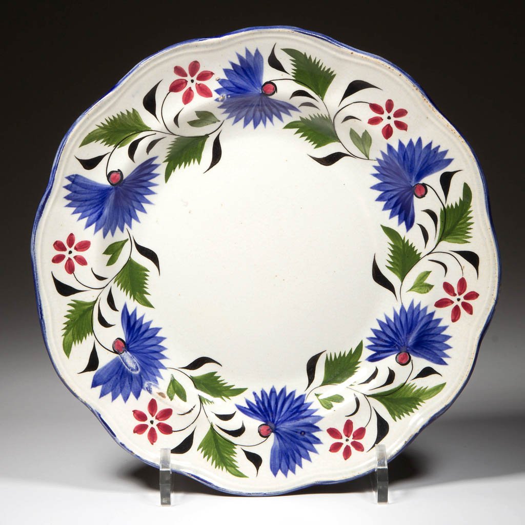 ENGLISH STAFFORDSHIRE POTTERY PEARLWARE MOLDED PLATE: ENGLISH STAFFORDSHIRE POTTERY PEARLWARE MOLDED PLATE, the shaped rim painted with blue edge above a wreath of "Thistle" flowers in blue, green, black and red above the undecorated face. Circa 1830-184