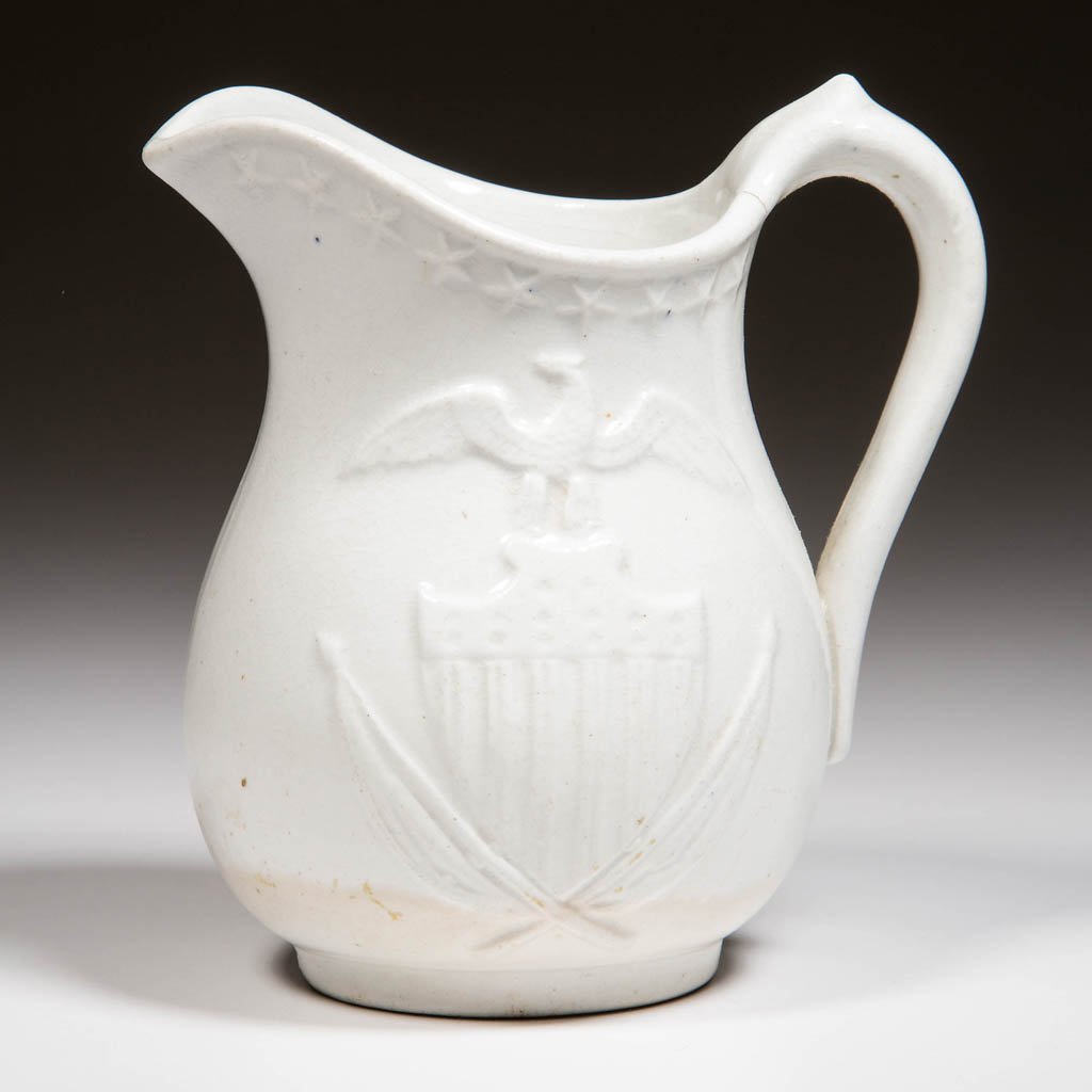 ENGLISH IRONSTONE POTTERY JUG MOLDED WITH AMERICAN: ENGLISH IRONSTONE POTTERY JUG MOLDED WITH AMERICAN STARS, SHIELD AND EAGLE, of pear-form with upraised spout, the band of stars just under the rim, each side molded with eagle above the shield and cro
