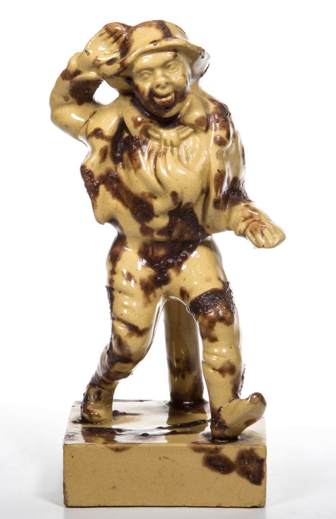 ENGLISH YORKSHIRE POTTERY YELLOWWARE FIGURE OF JIM CROW: ENGLISH YORKSHIRE POTTERY YELLOWWARE FIGURE OF JIM CROW, modeled as a standing figure of a man on a raised square base, the figure in full movement, dancing while leaning on a stump, painted with Rock