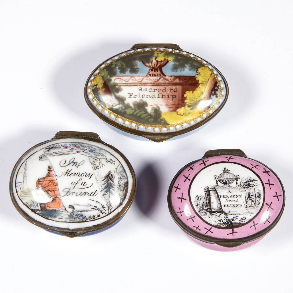 BATTERSEA / BILSTON ENAMEL SNUFF / PILL BOXES, LOT OF: BATTERSEA / BILSTON ENAMEL SNUFF / PILL BOXES, LOT OF THREE, each of oval form with hinged lid, featuring an urn and friendship motto, and mirror to lid interior. 18th/19th century. 1 1/4" x 1 5/8" to