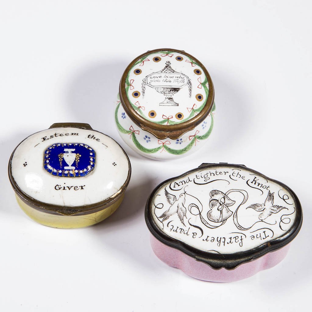 BATTERSEA / BILSTON ENAMEL SNUFF / PILL BOXES, LOT OF: BATTERSEA / BILSTON ENAMEL SNUFF / PILL BOXES, LOT OF THREE, circular and ovoid forms with hinged lid, two featuring an urn with motto, the other with birds, hearts, and ribbons surrounded by a motto,