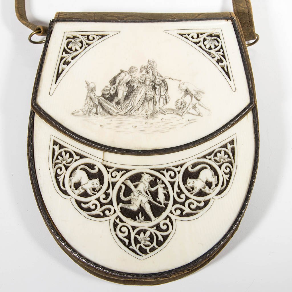 LADY'S PURSE: LADY'S PURSE, leather with pierce-carved and scrimshaw bone mounts depicting Puss 'n' Boots and a Royal family, with original leather handle. First quarter 20th century. 6" x 5" without handle.Provena