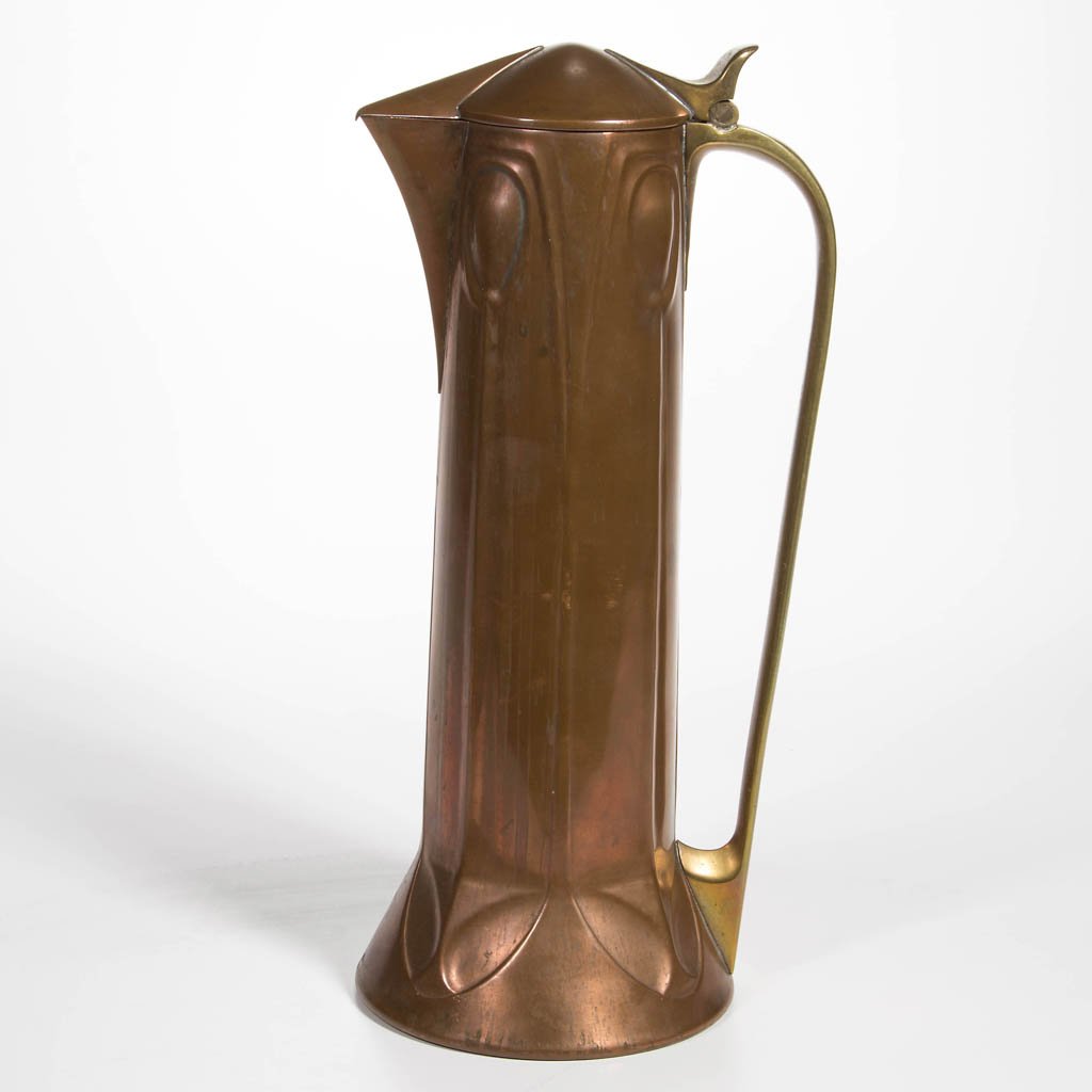 ALBIN MULLER (GERMAN, LATE 19TH / EARLY 20TH CENTURY): ALBIN MULLER (GERMAN, LATE 19TH / EARLY 20TH CENTURY) COPPER AND BRASS ARTS AND CRAFTS WINE JUG, of tall cylindrical form with flared base, brass handle, and hinged cover. Marked for Eduard Hueck, mak