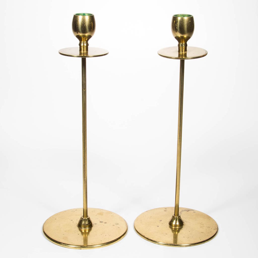 PAIR OF ARTS AND CRAFTS BRASS CANDLESTICKS: PAIR OF ARTS AND CRAFTS BRASS CANDLESTICKS, each with ovoid candle cup over a flattened drip pan raised on a long slender straight shaft resting on a flat circular base. First quarter 20th century. Ea