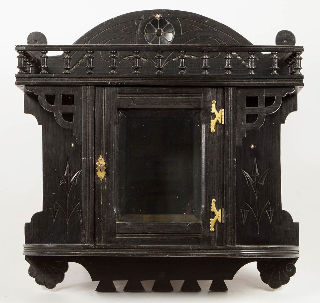 VICTORIAN EBONIZED HANGING WALL CABINET: VICTORIAN EBONIZED HANGING WALL CABINET, an Aesthetic Movement piece in the Eastlake style, featuring an upper shelf with gallery above a central hinged door fitted with a beveled glass pane flanked b