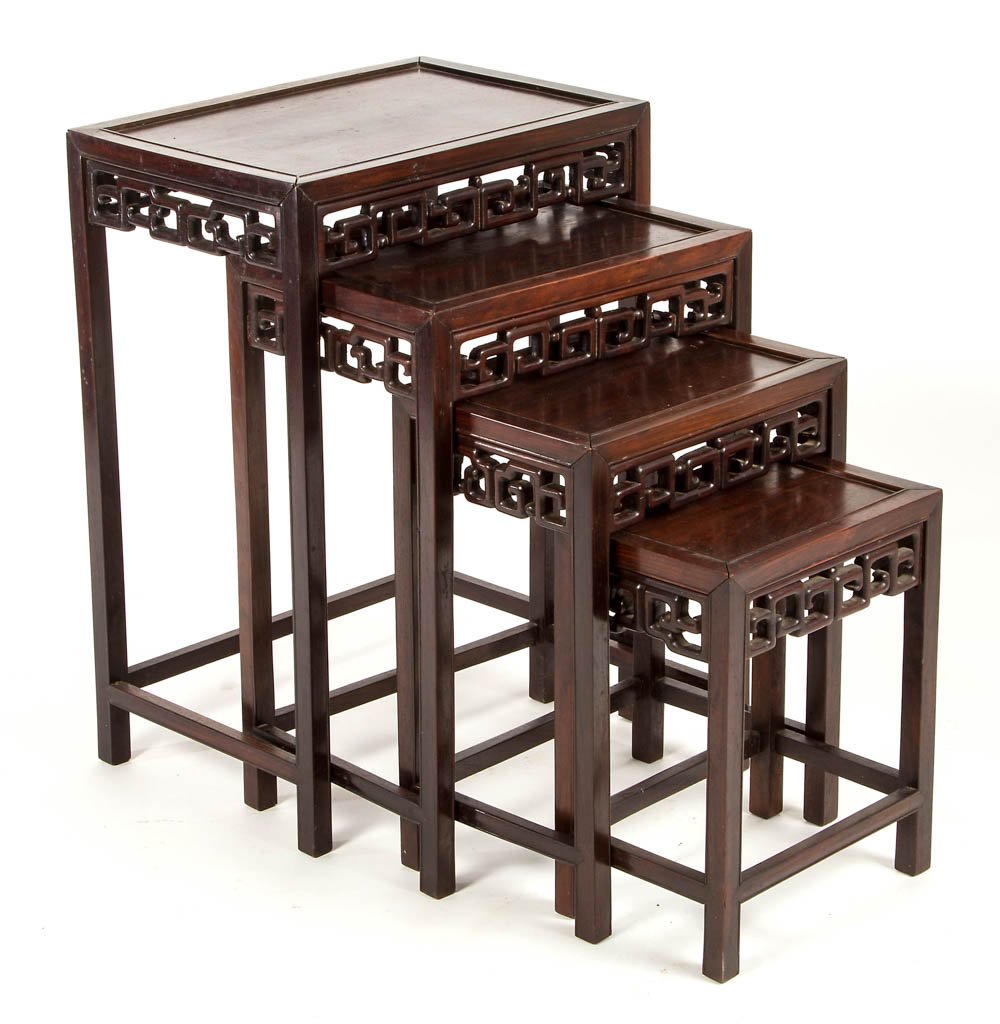 ASIAN CARVED ROSEWOOD SET OF FOUR NESTING TABLES: ASIAN CARVED ROSEWOOD SET OF FOUR NESTING TABLES, a graduated set with pierced sides and molded stretchers. Old surface with rich color. Purchased (c. 1955) by the consignor's parents in Japan. Mid 20