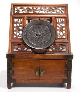 CHINESE CARVED WOODEN VANITY BOX AND BRONZE MIRROR, LOT: CHINESE CARVED WOODEN VANITY BOX AND BRONZE MIRROR, LOT OF TWO, of rosewood or a related wood, possibly "huali" or "huanghuali" wood, on four feet, with brass hardware and corner reinforcements, the t