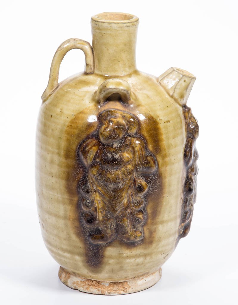 ASIAN EARTHENWARE FOOTED JUG: ASIAN EARTHENWARE FOOTED JUG, the foot lacking glaze, the body in yellow or clear glaze, with applied double-grooved handle to neck/shoulder, elongated cylindrical neck flanked by loop handles or lugs