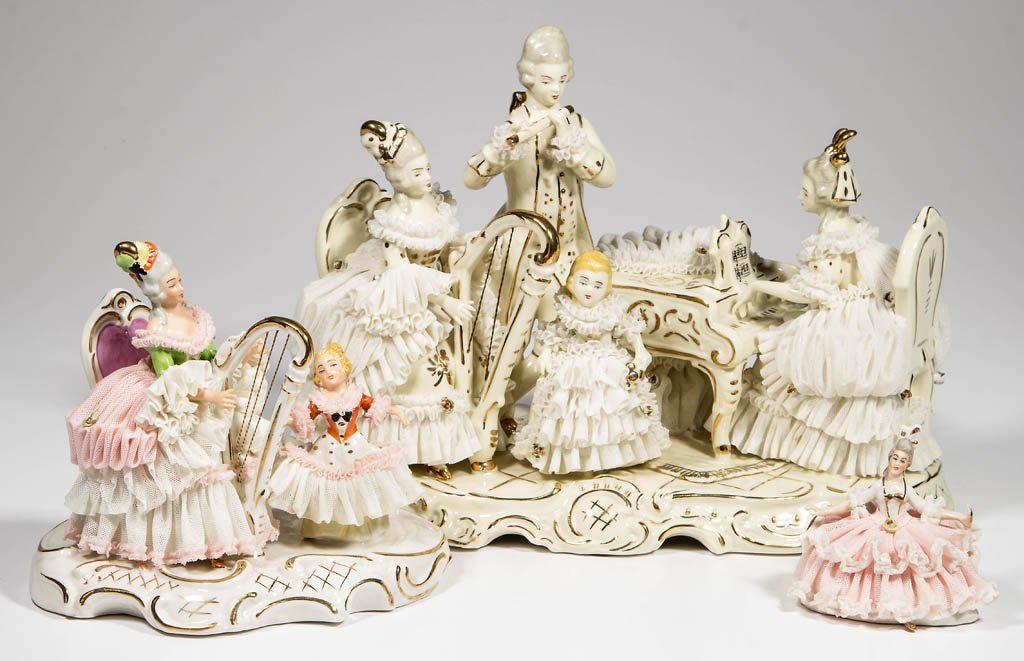DRESDEN-LACE GERMAN PORCELAIN FIGURES, LOT OF THREE: DRESDEN-LACE GERMAN PORCELAIN FIGURES, LOT OF THREE, comprising two musician groups and a single female seated on a settee. Each with underglaze-blue marking for Dresden-Art, Made in Germany. Second h