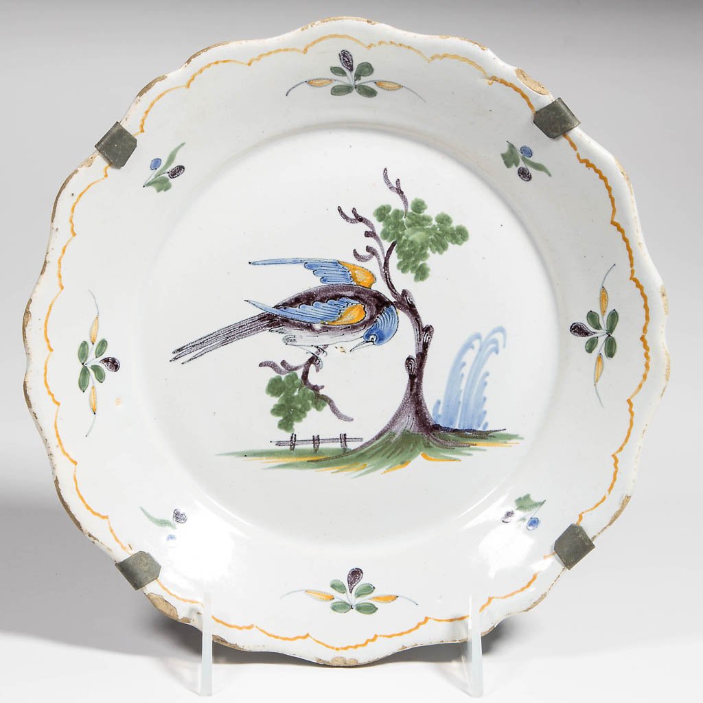 CONTINENTAL FAIENCE PLATE: CONTINENTAL FAIENCE PLATE, shaped rim, center featuring a polychrome peafowl in tree. Early handmade metal hanging cross hiding back mark. 18th or 19th century. 9" D.