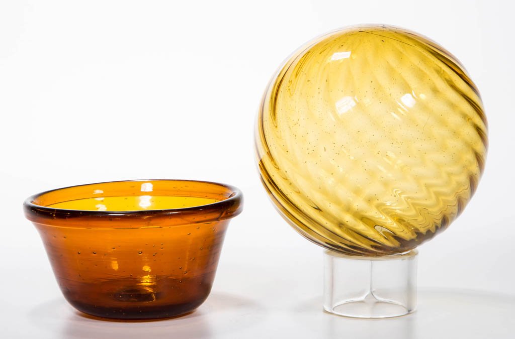 FREE-BLOWN DIMINUTIVE PAN: FREE-BLOWN DIMINUTIVE PAN, golden amber, deep conical form with folded rim and rough round base. Together with a yellow amber pattern-molded witch ball having 20 swirled ribs and a rough pontil mark w