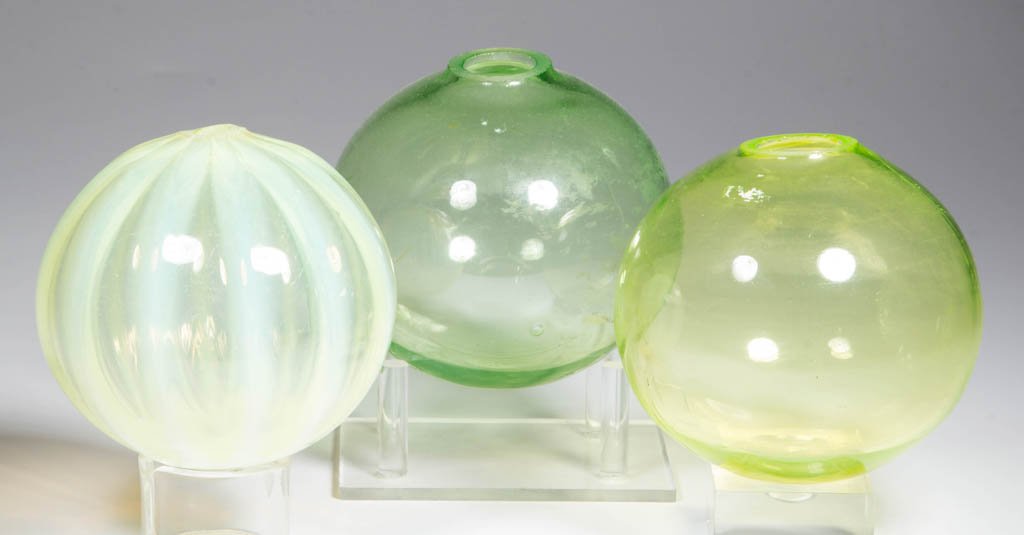 FREE-BLOWN WITCH BALLS, LOT OF THREE: FREE-BLOWN WITCH BALLS, LOT OF THREE, Vaseline (uranium), comprising two examples with a polished pontil mark and one opalescent ribbed example with a rough pontil mark, 3/8" to 1" openings. Late 19th