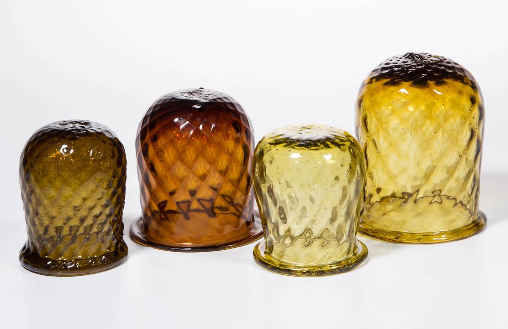 ASSORTED PATTERN-MOLDED CHRISTMAS LIGHTS, LOT OF FOUR: ASSORTED PATTERN-MOLDED CHRISTMAS LIGHTS, LOT OF FOUR, olive amber, brown amber, yellow amber, and golden amber, each diamond molded with folded rim and rough pontil mark. 19th century. 2 1/2" to 3 1/