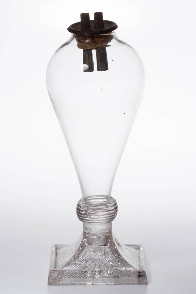 FREE-BLOWN AND PRESSED LACY WHALE OIL STAND LAMP: FREE-BLOWN AND PRESSED LACY WHALE OIL STAND LAMP, colorless, bulb font raised on a square lacy base with alternating Princes Feather Medallion and Shell designs on interior stippled panels, beehive wa