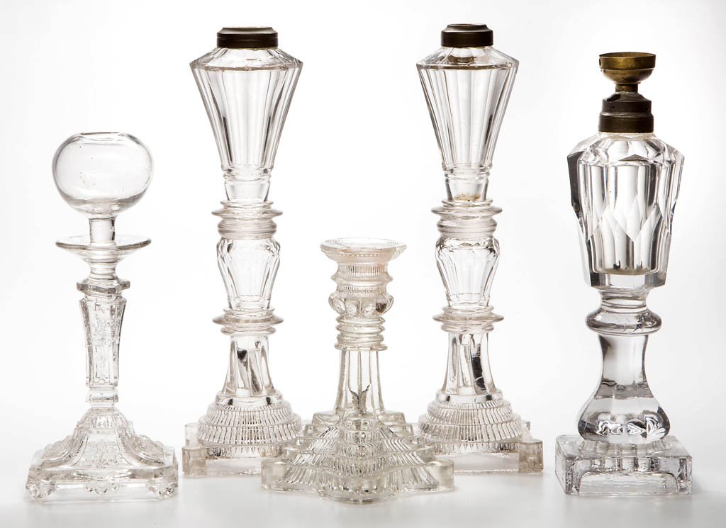ASSORTED BLOWN AND PRESSED LIGHTING DEVICES, LOT OF: ASSORTED BLOWN AND PRESSED LIGHTING DEVICES, LOT OF FIVE, colorless, including a pair of panel-cut three-part stand lamps and a lace maker's lamp. 19th century. 6 3/4" to 12 1/2" H. Provenance: Lowell