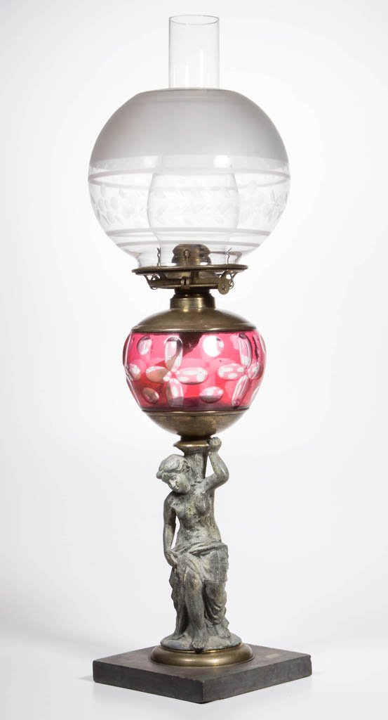 J. F. IDEN CUT OVERLAY AND FIGURAL STEM KEROSENE STAND: J. F. IDEN CUT OVERLAY AND FIGURAL STEM KEROSENE STAND LAMP, ruby to colorless globular font with cut quatrefoils and punties, font base embossed "IDEN", spelter stem of lady holding urn and a single-