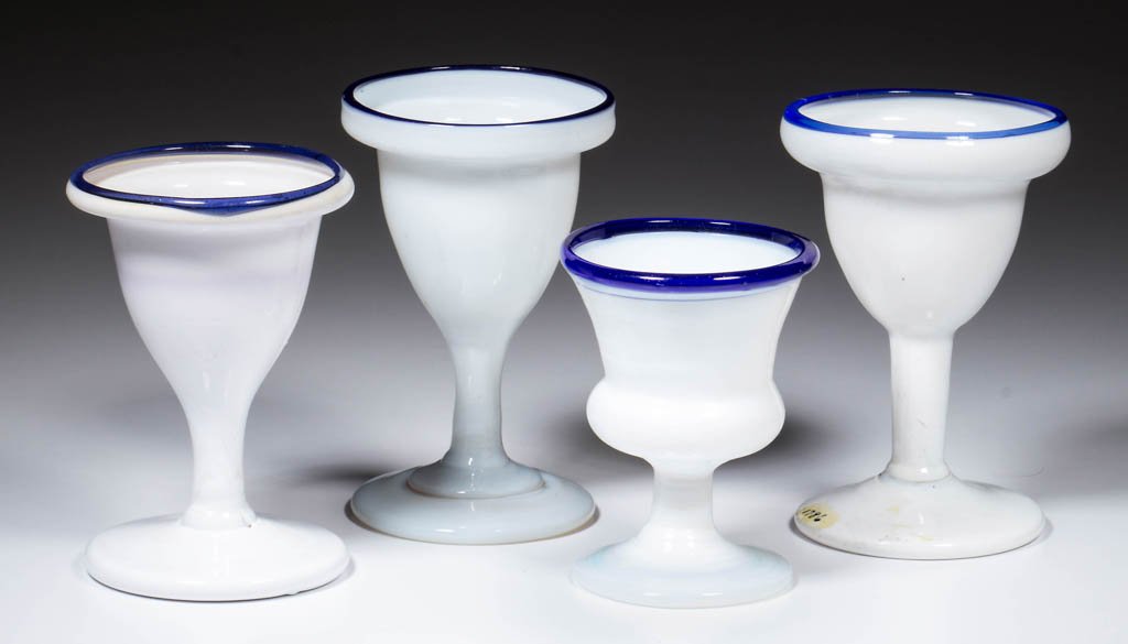 FREE-BLOWN FOOTED SALTS / EGG CUPS, LOT OF FOUR: FREE-BLOWN FOOTED SALTS / EGG CUPS, LOT OF FOUR, comprising a deep fiery opalescent low-foot example with applied cobalt blue rim, and three opal opaque high-foot examples with various blue colored ap