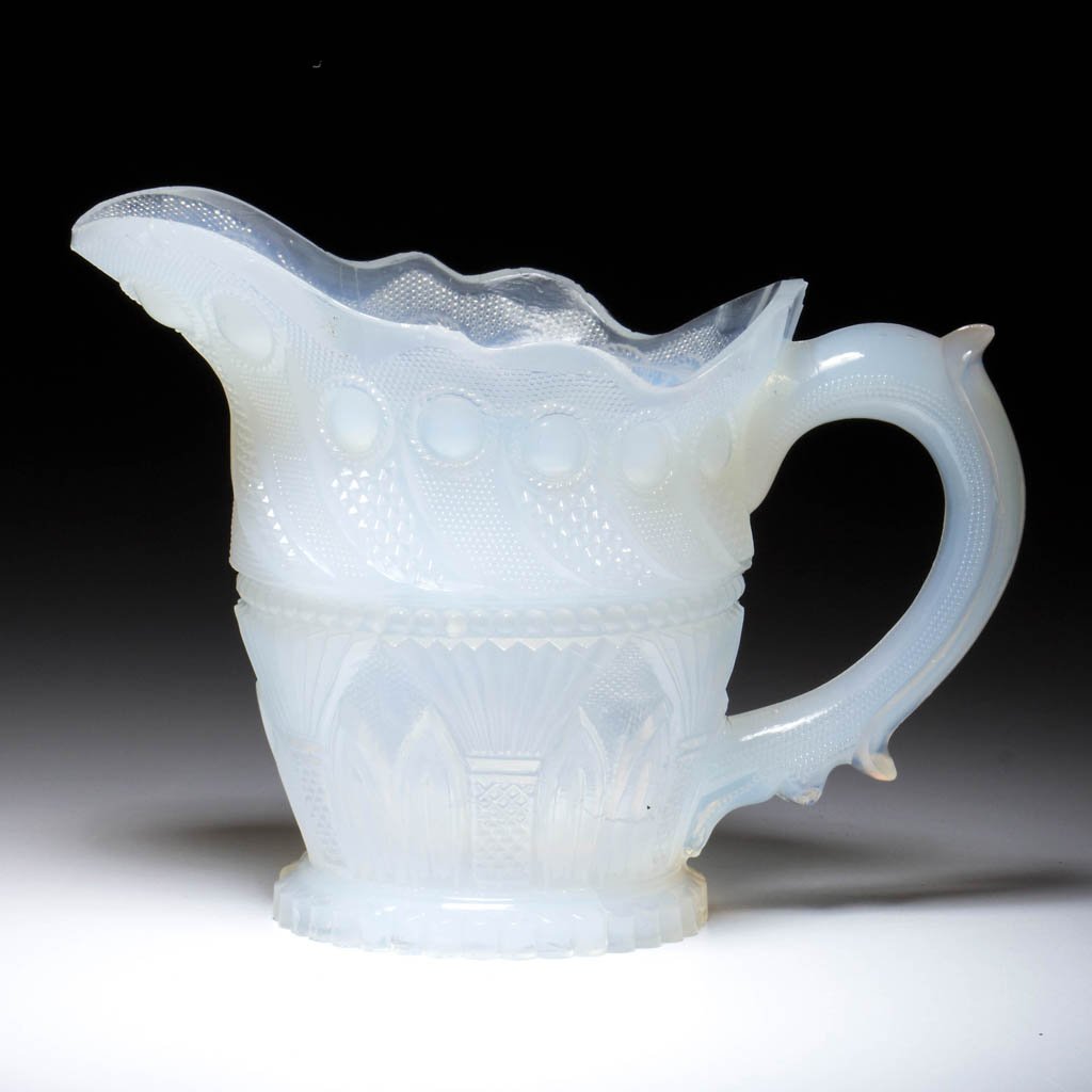 PRESSED LACY PEACOCK EYE AND GOTHIC ARCH CREAMER: PRESSED LACY PEACOCK EYE AND GOTHIC ARCH CREAMER, strong fiery opalescent, slight barrel-form with a scalloped rim and molded handle, raised on a circular 36-scallop foot, rayed under base with center