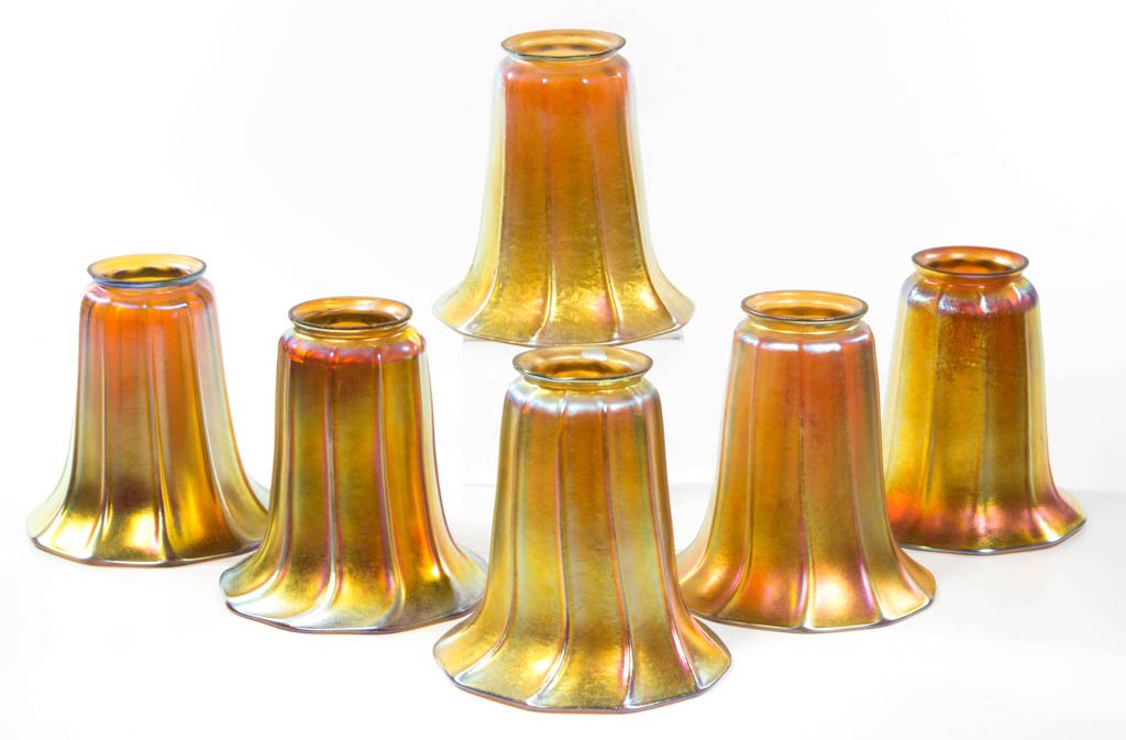 STEUBEN-TYPE ART GLASS LAMP SHADES, LOT OF SIX: STEUBEN-TYPE ART GLASS LAMP SHADES, LOT OF SIX, golden iridescent, each with a factory-polished rim, four examples with a spot of silver paint to the lip, possibly smudged marks, another with a Steube