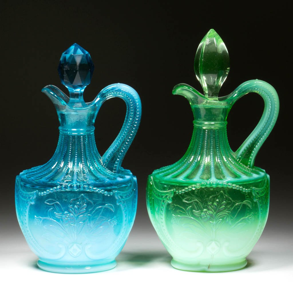 WILD BOUQUET CRUETS, LOT OF TWO: WILD BOUQUET CRUETS, LOT OF TWO, blue and green opalescent, each with a matching colored period stopper. Northwood Glass Co./Dugan Glass Co. Circa 1903. 6 1/2" and 7" HOA. Literature: Heacock – Book