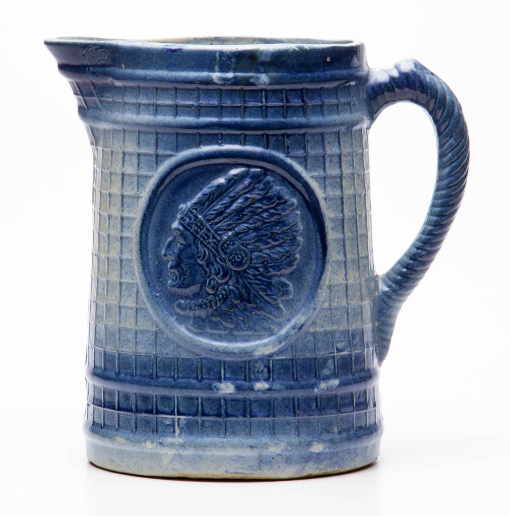 BLUE AND WHITE SALT-GLAZED CERAMIC PITCHER: BLUE AND WHITE SALT-GLAZED CERAMIC PITCHER, rich blue color, Indian in War Bonnet pattern. First quarter 20th century. 8 1/4" H.Literature: Taylor/Lowrance - Salt Glaze Stoneware, p. 55.Provenance: Fr