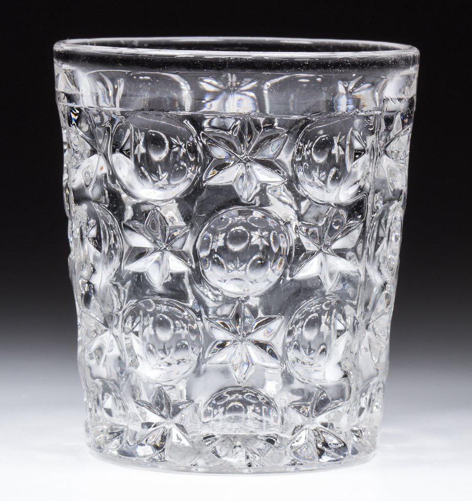 EARLY MOON AND STAR WATER TUMBLER: EARLY MOON AND STAR WATER TUMBLER, colorless lead glass, rayed base. Boston & Sandwich Glass Co. and possibly others. Circa 1850-1870. 3 1/2" H, 2 1/2" D base. Literature: Parallels B & K I, fig. 1191