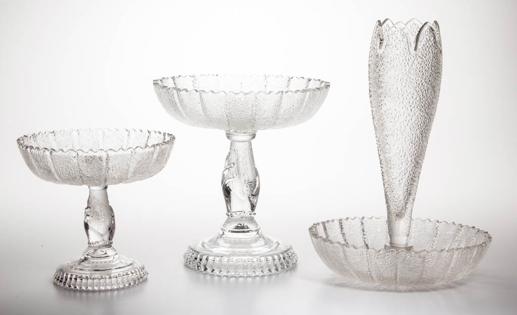 TREE OF LIFE EPERGNES, LOT OF THREE: TREE OF LIFE EPERGNES, LOT OF THREE, colorless, comprising two epergne bases with hand standard, and a bowl-form example with vase insert. Hobbs, Brockunier & Co. Circa 1879. 6 1/8" to 11 1/8" HOA.Lit
