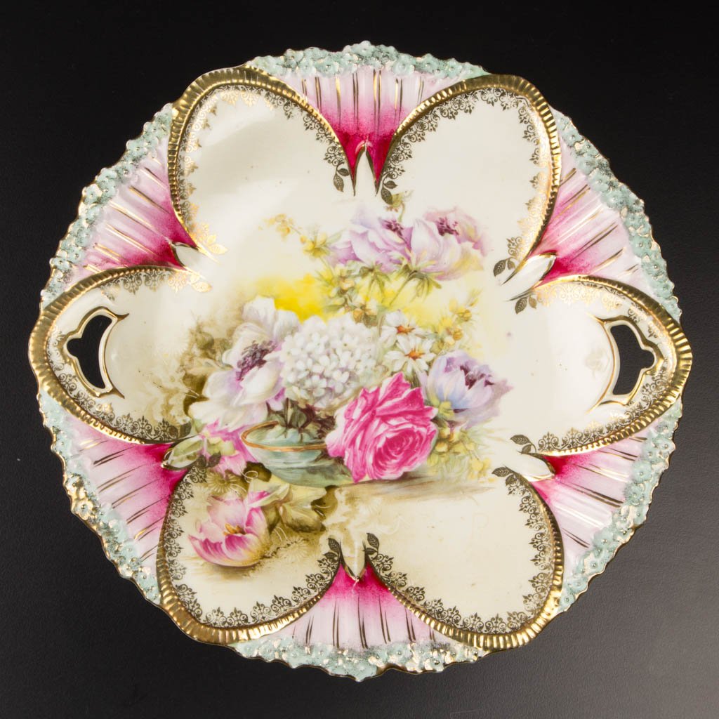 R. S. PRUSSIA PORCELAIN CAKE PLATE: R. S. PRUSSIA PORCELAIN CAKE PLATE, with gold-painted and -stenciled decoration, mold 91, with printed bouquet in glass bowl decoration; with red and green Prussia wreath and star printed mark. Late 1