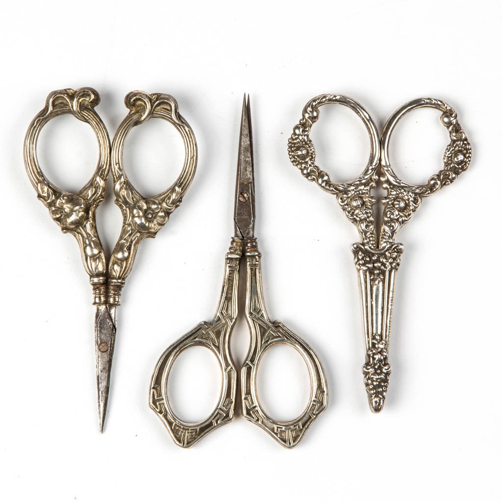 ASSORTED STERLING SILVER SEWING SCISSORS, LOT OF THREE: ASSORTED STERLING SILVER SEWING SCISSORS, LOT OF THREE, various patterns including two repouse examples, one fitted in a sheath with illegible maker's mark on side. Late 19th/early 20th century. 3 3/4