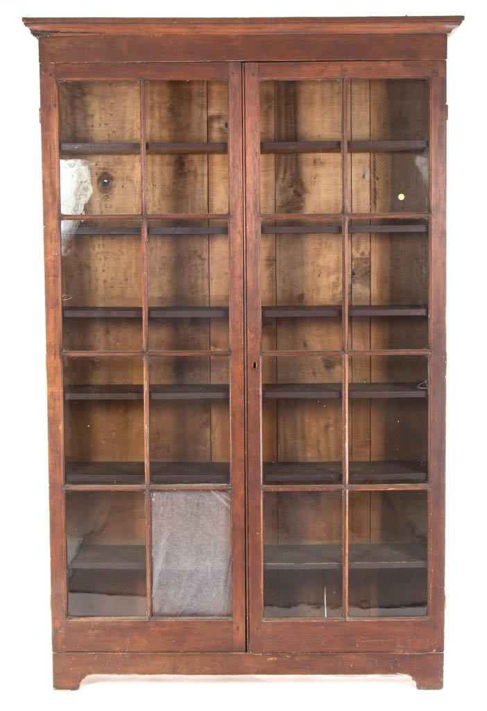VIRGINIA PINE AND POPLAR BOOK PRESS / CASE: VIRGINIA PINE AND POPLAR BOOK PRESS / CASE, the applied molded cornice above two tall hinged eight-pane doors with through-mortised joints, concealing six fixed shelves, raised on simple cut-out feet.