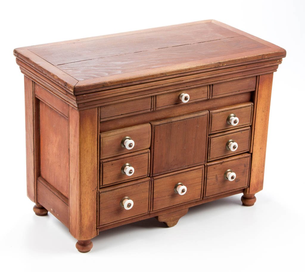 AMERICAN PAINTED PINE AND POPLAR SPICE CHEST: AMERICAN PAINTED PINE AND POPLAR SPICE CHEST, the hinged rectangular lid concealing a divided upper interior over a case with eight drawers, raised on small turned feet. Retains a red-washed surface.