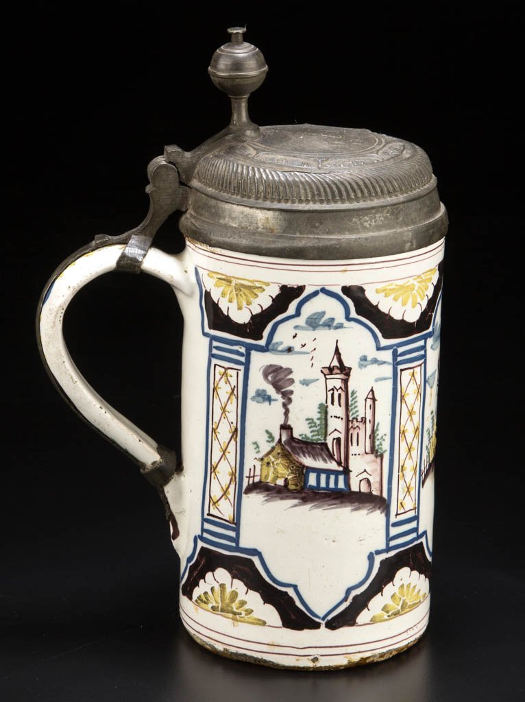 CONTINENTAL TIN-GLAZED FAIENCE PEWTER-MOUNTED TANKARD: CONTINENTAL TIN-GLAZED FAIENCE PEWTER-MOUNTED TANKARD STEIN, the straight-sided body painted in manganese brown, ocher, cobalt blue and green with a stylized farm and church, in three reserved cartouc