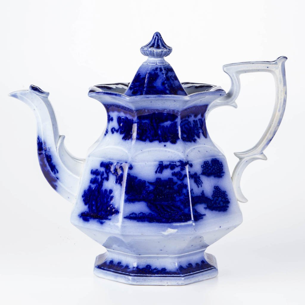 ENGLISH W. RIDGWAY IRONSTONE FLOW BLUE "FORMOSA": ENGLISH W. RIDGWAY IRONSTONE FLOW BLUE "FORMOSA" PATTERN TEAPOT AND COVER, transfer printed, of scallop-molded octagonal-panelled form, the pattern printed in very dark blue to the body below the Asia