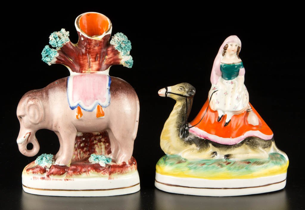 ENGLISH STAFFORDSHIRE POTTERY FIGURAL GROUPS, LOT OF: ENGLISH STAFFORDSHIRE POTTERY FIGURAL GROUPS, LOT OF TWO, comprising an example with a blanketed elephant standing on an oval grass-encrusted mound, a tree-trunk-form spill vase issuing from his back,