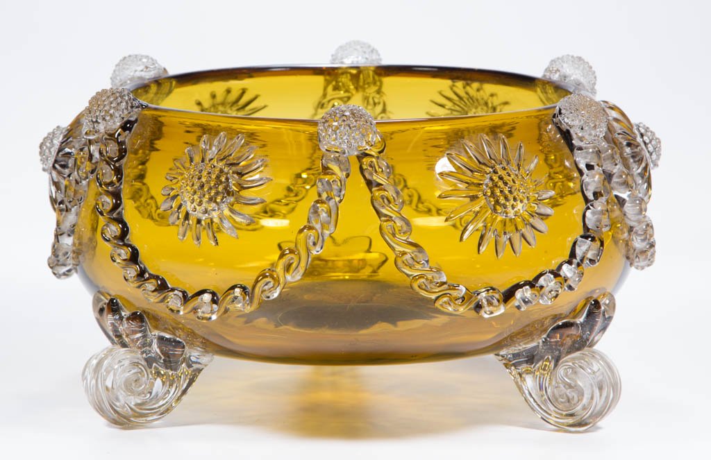 ENGLISH VICTORIAN GLASS LARGE BOWL: ENGLISH VICTORIAN GLASS LARGE BOWL, amber, with applied colorless rigaree swags, stars, and raspberry prunts, raised on three colorless shell feet, applied prunt to pontil mark. Attributed to Stuart a