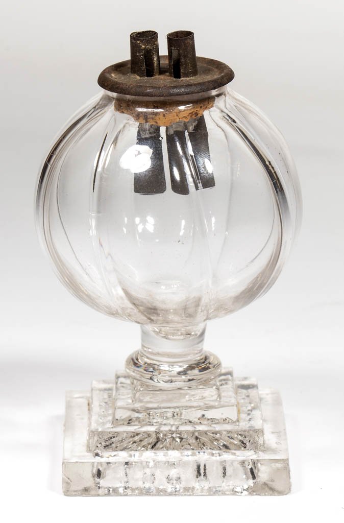PATTERN-MOLDED AND PRESSED WHALE OIL SPARKING LAMP: PATTERN-MOLDED AND PRESSED WHALE OIL SPARKING LAMP, colorless, globular-form font molded with eight vertical ribs, short drawn stem, raised on a four-step square base, underside with petal pattern and