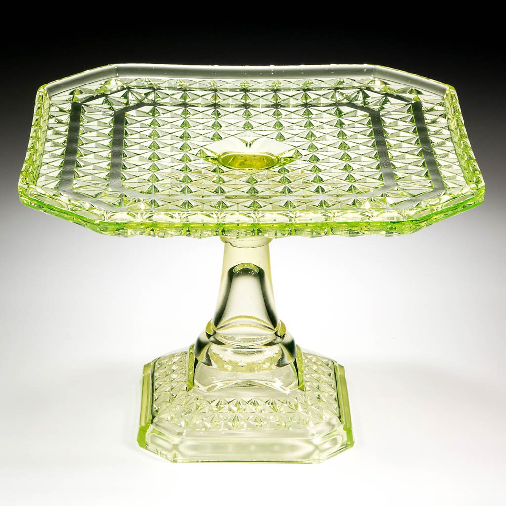 HEAVY PANELLED FINECUT SALVER / CAKE STAND: HEAVY PANELLED FINECUT SALVER / CAKE STAND, Vaseline (black lighted). Fourth quarter 19th century. 6 5/8" H, 9" SQ. Provenance: From the collection of the late Ed Kleppinger of New Orleans, LA.