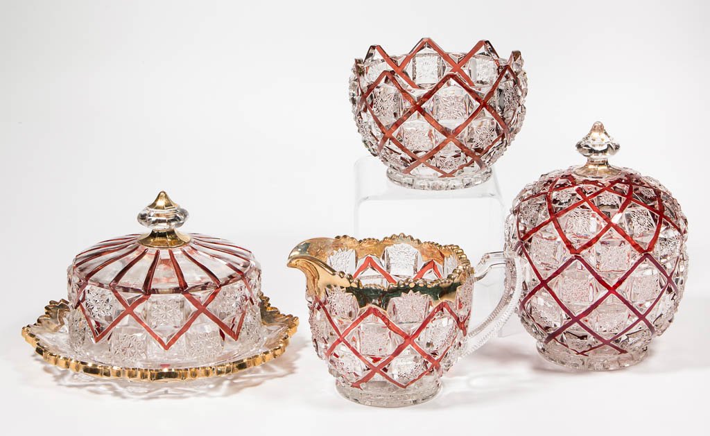 OLD QUILT - RUBY-STAINED FOUR-PIECE TABLE SET: OLD QUILT - RUBY-STAINED FOUR-PIECE TABLE SET, colorless with gilt decoration, comprising a covered butter dish, covered sugar bowl, creamer, and spooner. Westmoreland Specialty Co. Circa 1910. 3 1/2"