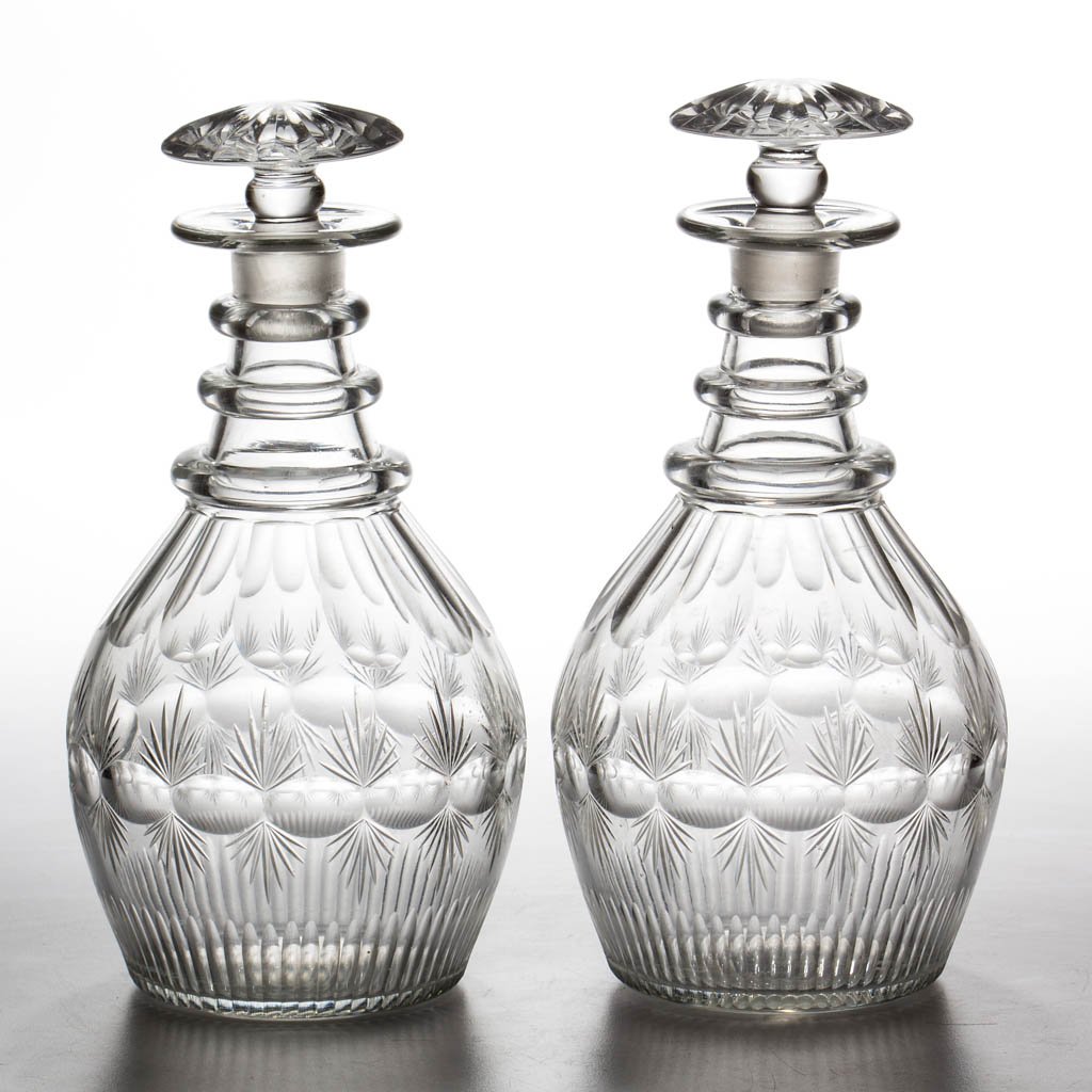 CUT DOUBLE-FAN AND THUMBPRINT BAND PAIR OF QUART: CUT DOUBLE-FAN AND THUMBPRINT BAND PAIR OF QUART DECANTERS, colorless lead glass, Prussian form, each shoulder panels, basal flutes, three applied plain neck rings, and polished pontil mark, matching 