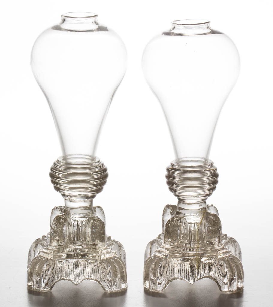 FREE-BLOWN AND PRESSED WHALE OIL STAND LAMP: FREE-BLOWN AND PRESSED WHALE OIL STAND LAMP, colorless, bulb-form font, raised on a complex base featuring four upright columns each topped with a lion mask around stem, and a quatrefoil-shape foot wi