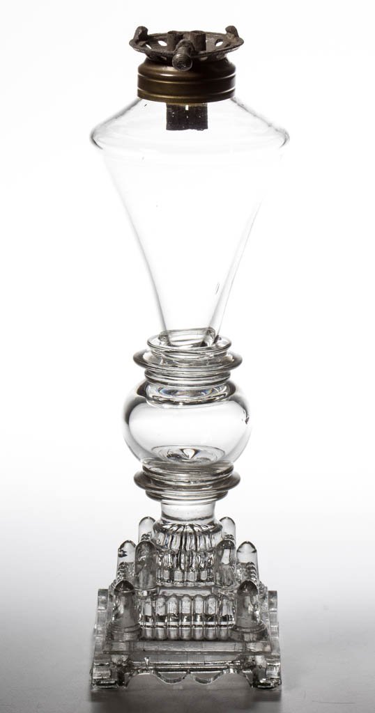 FREE-BLOWN AND PRESSED WHALE OIL STAND LAMP: FREE-BLOWN AND PRESSED WHALE OIL STAND LAMP, colorless, conical font raised on a hollow globular knop stem and a complex three-step circular base featuring protruding tapered columns on the corners an