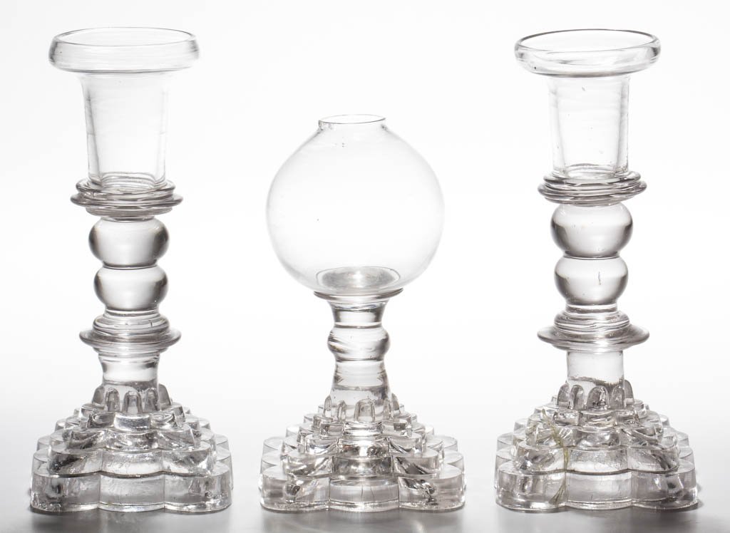 FREE-BLOWN AND PRESSED LIGHTING DEVICES, LOT OF THREE: FREE-BLOWN AND PRESSED LIGHTING DEVICES, LOT OF THREE, colorless, comprising a globular font whale oil lamp and pair of free-blown socket, double-knop candlesticks, each raised on a four-step eight-pe