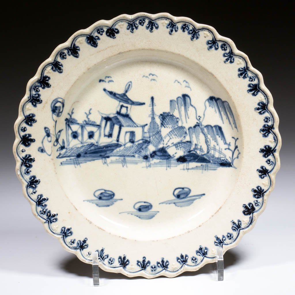 ENGLISH CREAMWARE CHINOISERIE CERAMIC PLATE: ENGLISH CREAMWARE CHINOISERIE CERAMIC PLATE, having a finely embossed and scalloped edge detailed in blue, and a blue house or pagoda with fence and landscape painted in center. Impressed with a six-p