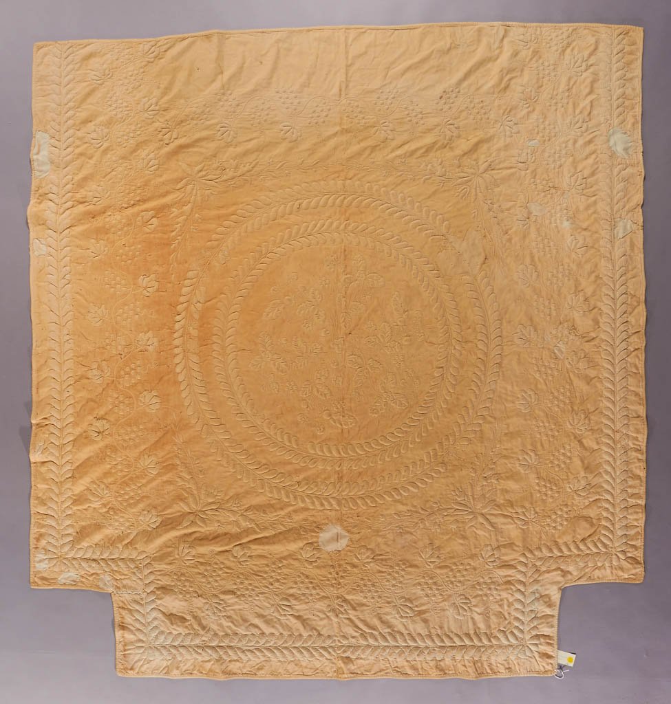 AMERICAN TRAPUNTO WHITEWORK QUILT: AMERICAN TRAPUNTO WHITEWORK QUILT, with cutouts for bed posts, central floral design within double wreath border, surrounded by tulip corner brackets and grapevine; outer border matching inner wreaths