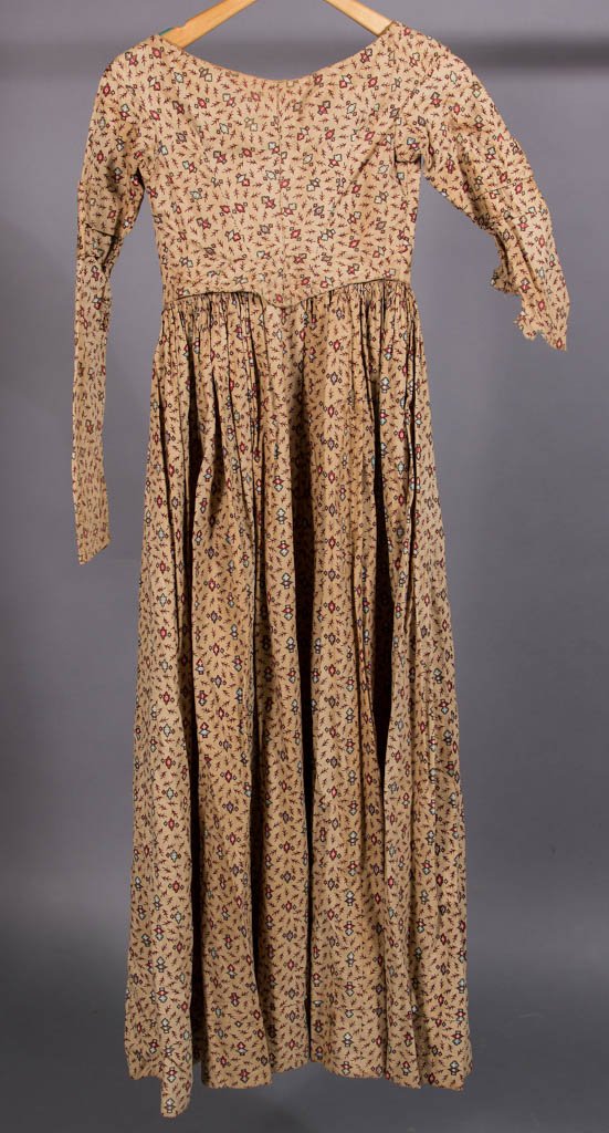 VICTORIAN MULTI-PRINT COTTON DRESS: VICTORIAN MULTI-PRINT COTTON DRESS, red and blue print on brown field. 1855-1865. 54" LOA, 22" waist. Very good, little staining, Right sleeve has bottom half missing. Period repairs well done. Proven