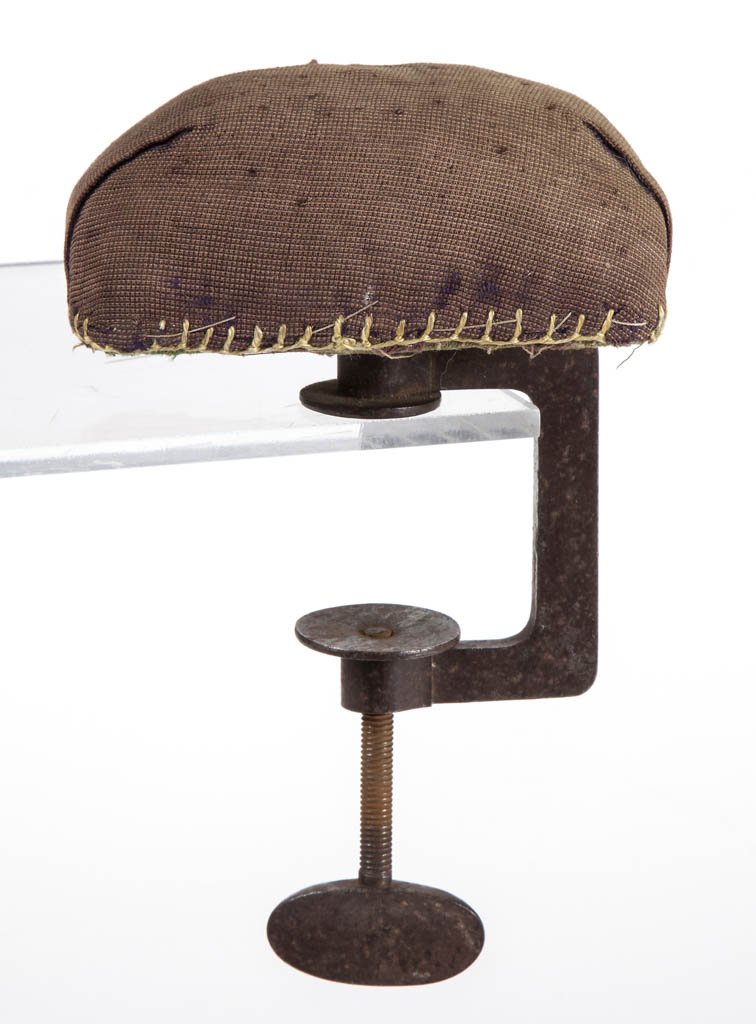 CUT STEEL SEWING CLAMP WITH CUSHION: CUT STEEL SEWING CLAMP WITH CUSHION, simple c-form example with ovoid-form and slightly concave thumbwheel, rectangular-form pin cushion top with original brown cloth top, underside with green cloth a