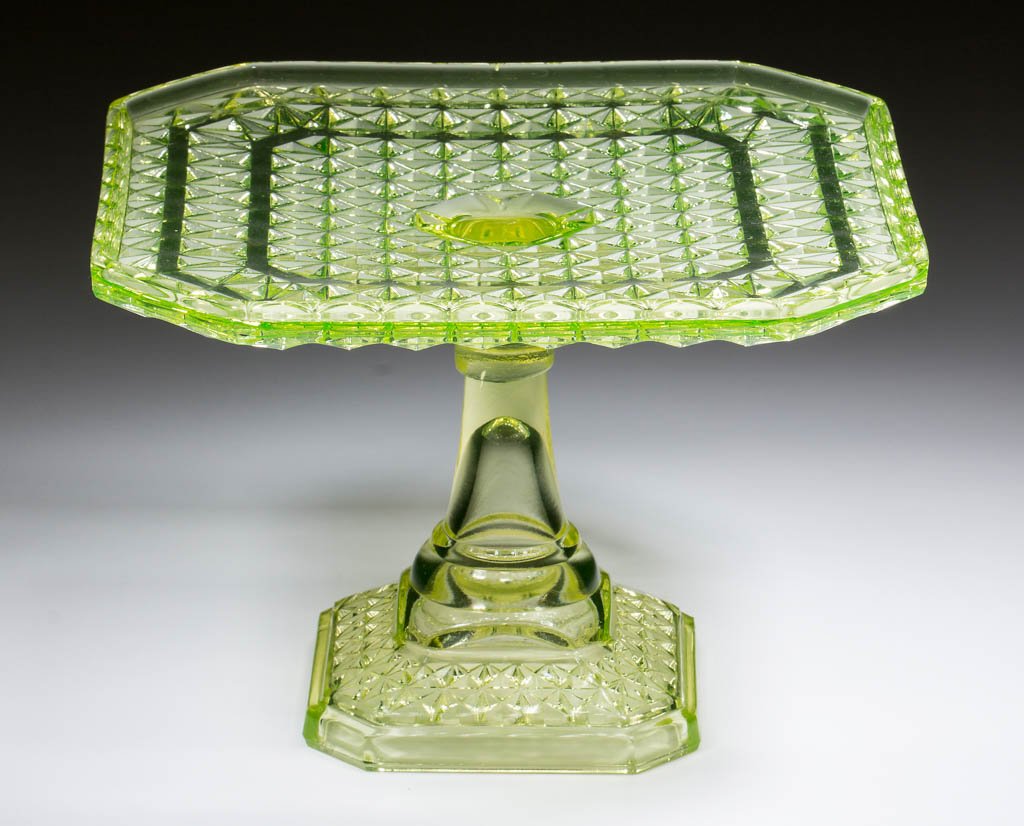PRESSED FINECUT CAKE STAND: PRESSED FINECUT CAKE STAND, Vaseline (black lighted). Maker unverified. Fourth quarter 19th century. 5 7/8" H, 8" SQ. Virtually undamaged with a single pattern flake to the underside of the plate. Pro