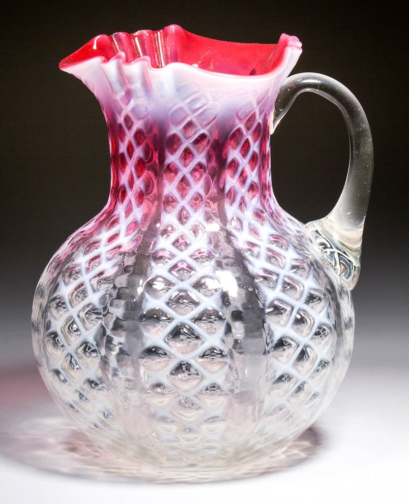 CRISS-CROSS WATER PITCHER: CRISS-CROSS WATER PITCHER, rubina opalescent, applied colorless handle, polished pontil mark. Consolidated Lamp & Glass Co. Circa 1888. 8 5/8" H.Nearly undamaged with a minute flake to the rim.Literat