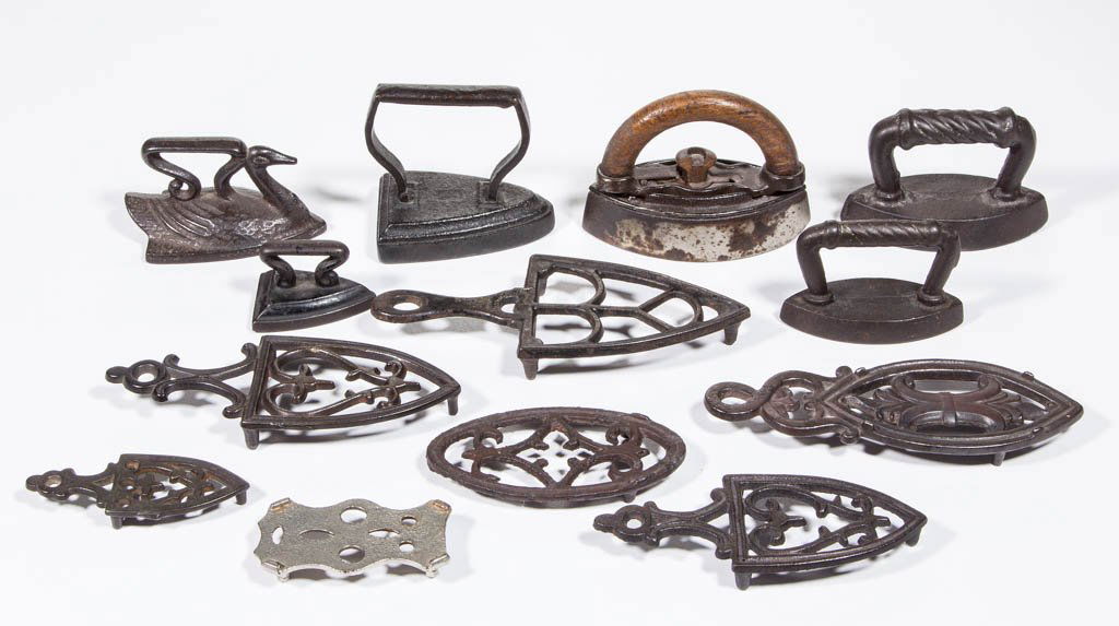 ASSORTED CAST-IRON SMALL SAD IRONS AND TRIVETS, LOT OF: ASSORTED CAST-IRON SMALL SAD IRONS AND TRIVETS, LOT OF 13, including one sad iron molded in the shape of a swan, one with removable wooden handle, and pierced trivets. Second half 19th/early 20th cent