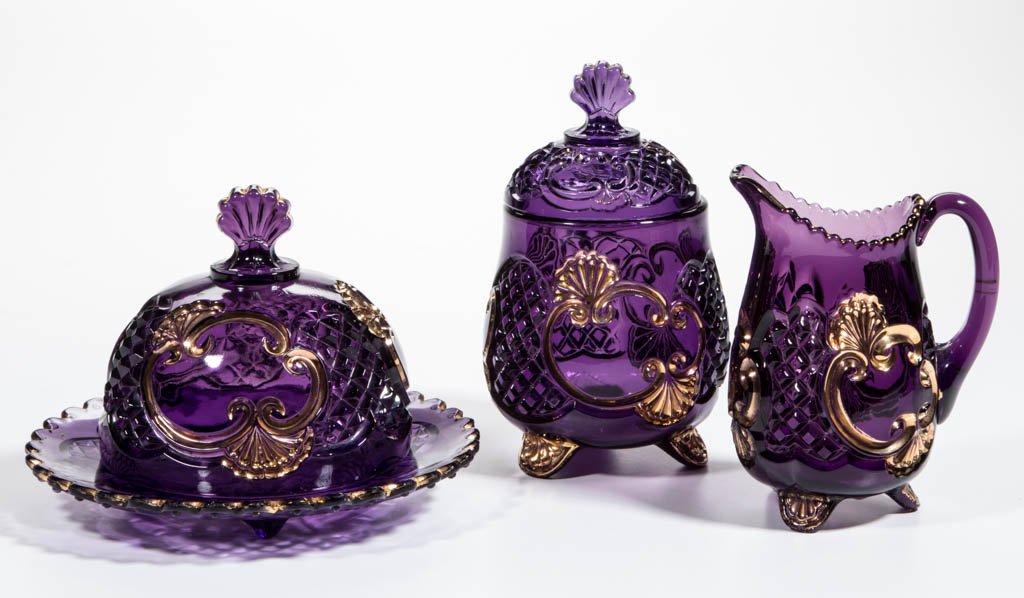RIVERSIDE NO. 484 (OMN) / CROESUS TABLE ARTICLES, LOT: RIVERSIDE NO. 484 (OMN) / CROESUS TABLE ARTICLES, LOT OF THREE, amethyst with gilt decoration, comprising a covered butter dish, covered sugar bowl, and creamer. Riverside Glass Works. Circa 1898. 5 1